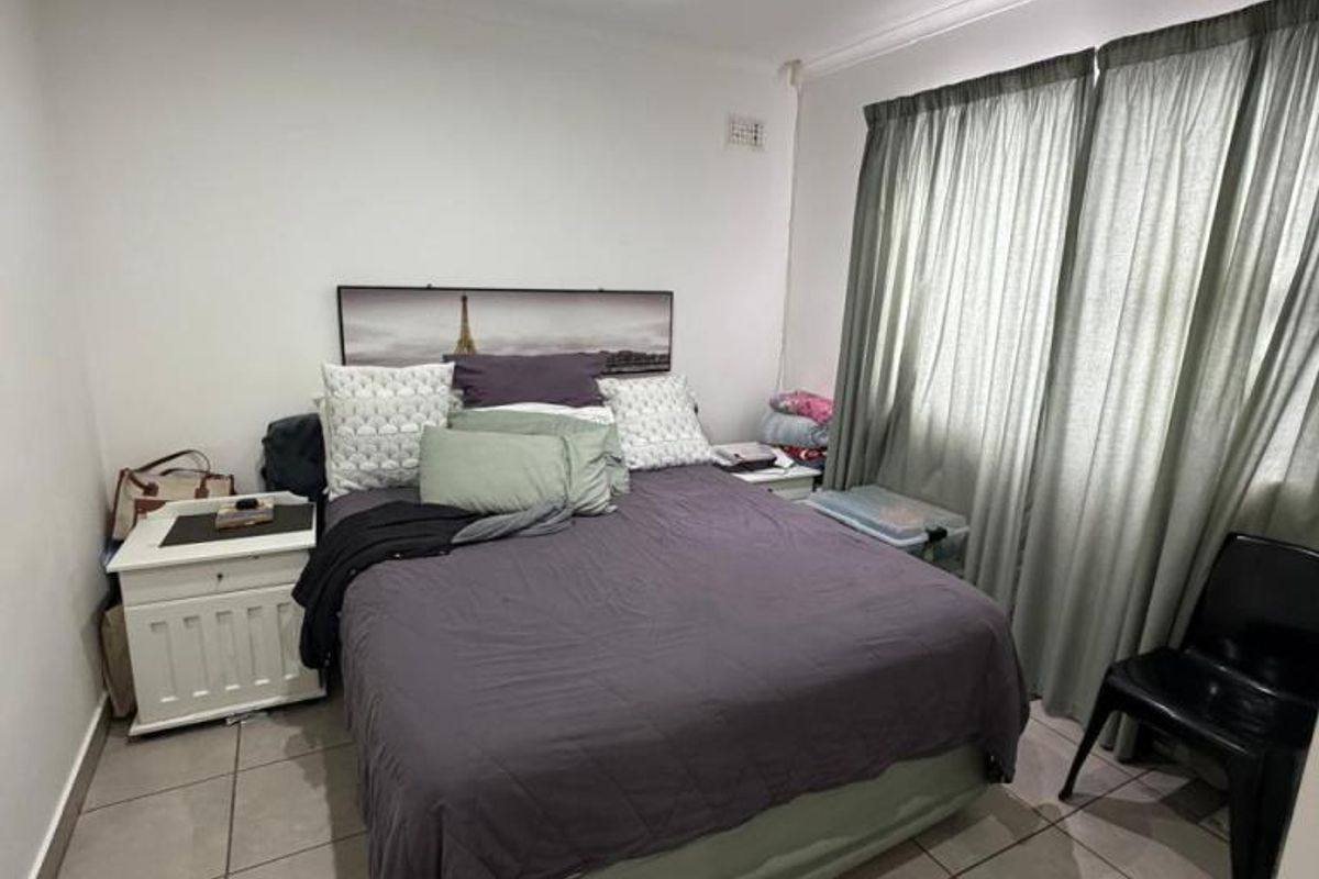 A functional bedroom featuring tiled flooring and recessed downlighting, providing a neutral base for personalization.