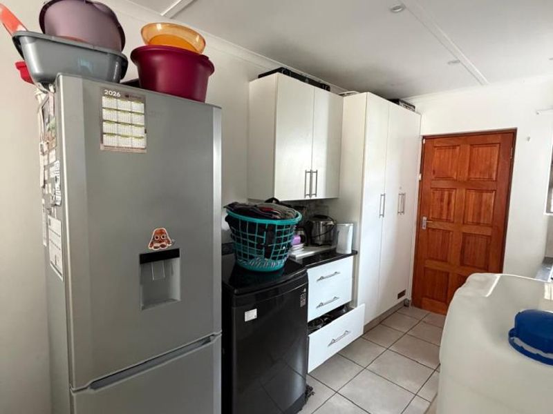 A functional laundry area featuring tiled flooring, built-in cabinetry for storage, and recessed ceiling lighting.