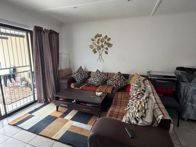 A living room featuring tiled flooring, recessed downlights, and a sliding glass door providing access to an outdoor area.