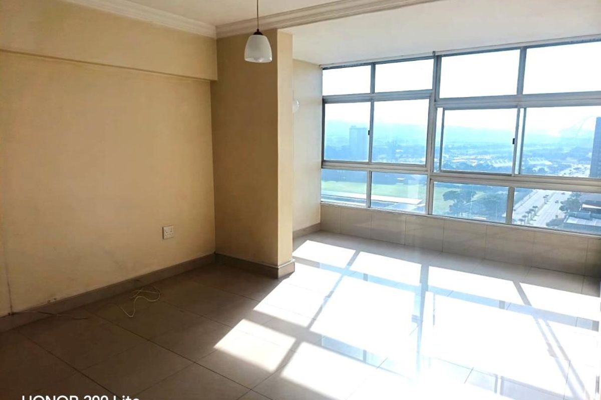An empty, sunlit living area featuring large windows with expansive views, tiled flooring, and a neutral color palette, ready for personalization.