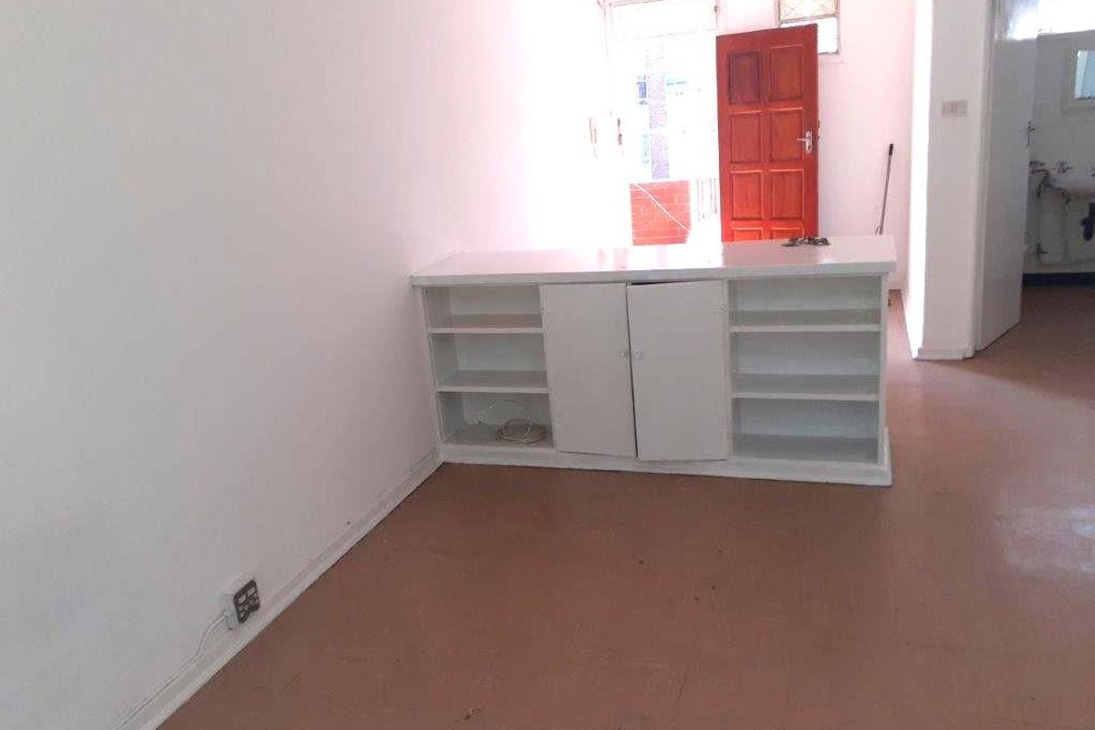 An empty living area featuring built-in white cabinetry and tiled flooring, offering a blank canvas for renovation or interior design.