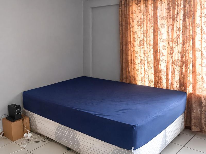 A bedroom featuring neutral grey walls and tiled flooring, providing a simple and functional space.