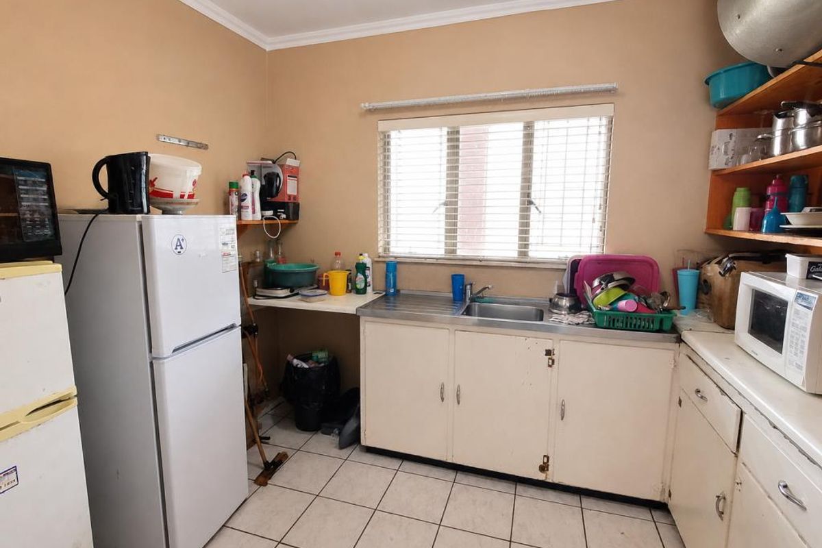 A functional kitchen featuring tiled flooring, a stainless steel sink, and built-in cabinetry, offering potential for modernization and cosmetic updates.