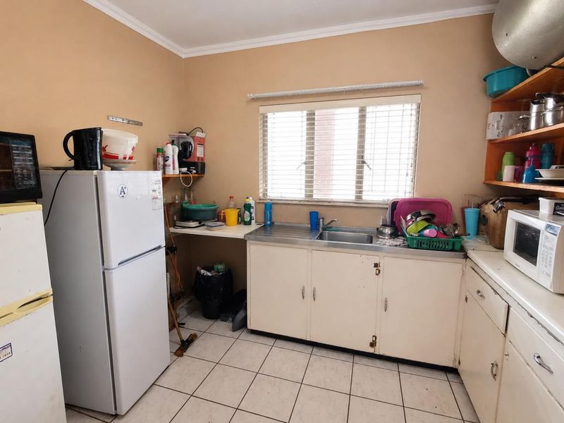 A functional kitchen featuring tiled flooring, a stainless steel sink, and built-in cabinetry, offering potential for modernization and cosmetic updates.