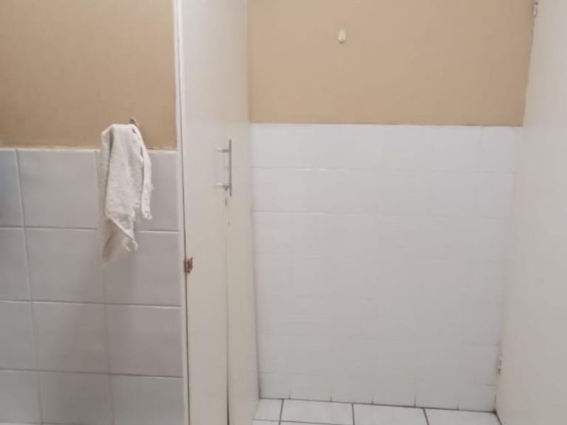 A functional laundry area featuring tiled flooring, a tiled splashback, and built-in storage cabinetry.