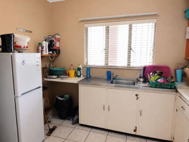A functional kitchen featuring built-in cabinetry, a stainless steel sink, and tiled flooring, offering potential for modernization and cosmetic updates.