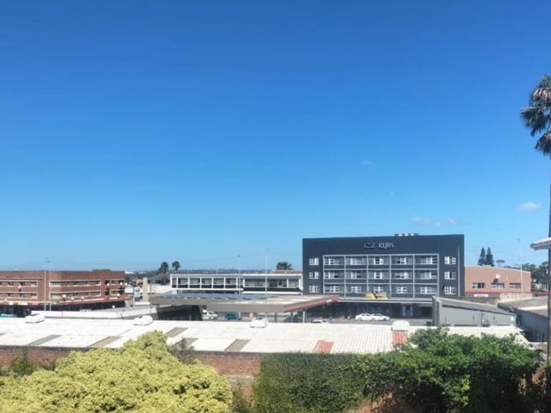 An elevated urban view overlooking surrounding commercial buildings and neighborhood infrastructure under a clear blue sky.