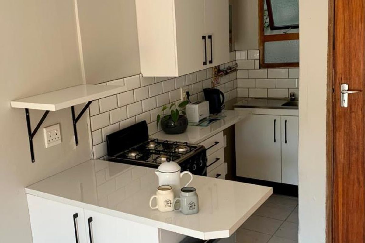 Compact kitchen featuring white cabinetry, subway tile backsplash, gas hob, and stone countertops with a breakfast bar extension.