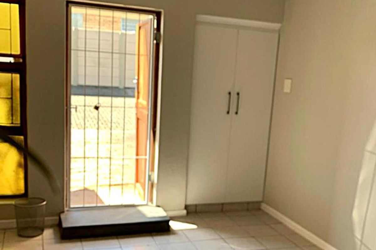 An empty entrance area featuring tiled flooring, a built-in cupboard, and a secure external door leading to the exterior.