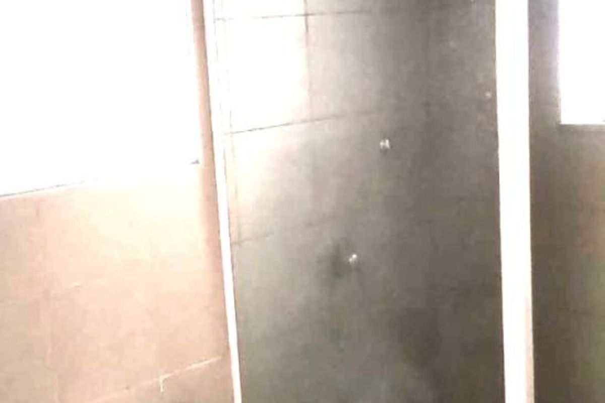 A compact bathroom featuring a shower enclosure with a glass door and a standard toilet, finished with neutral wall tiling.