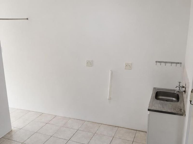 A functional laundry area featuring tiled flooring, a stainless steel sink, and dedicated plumbing connections for appliances.