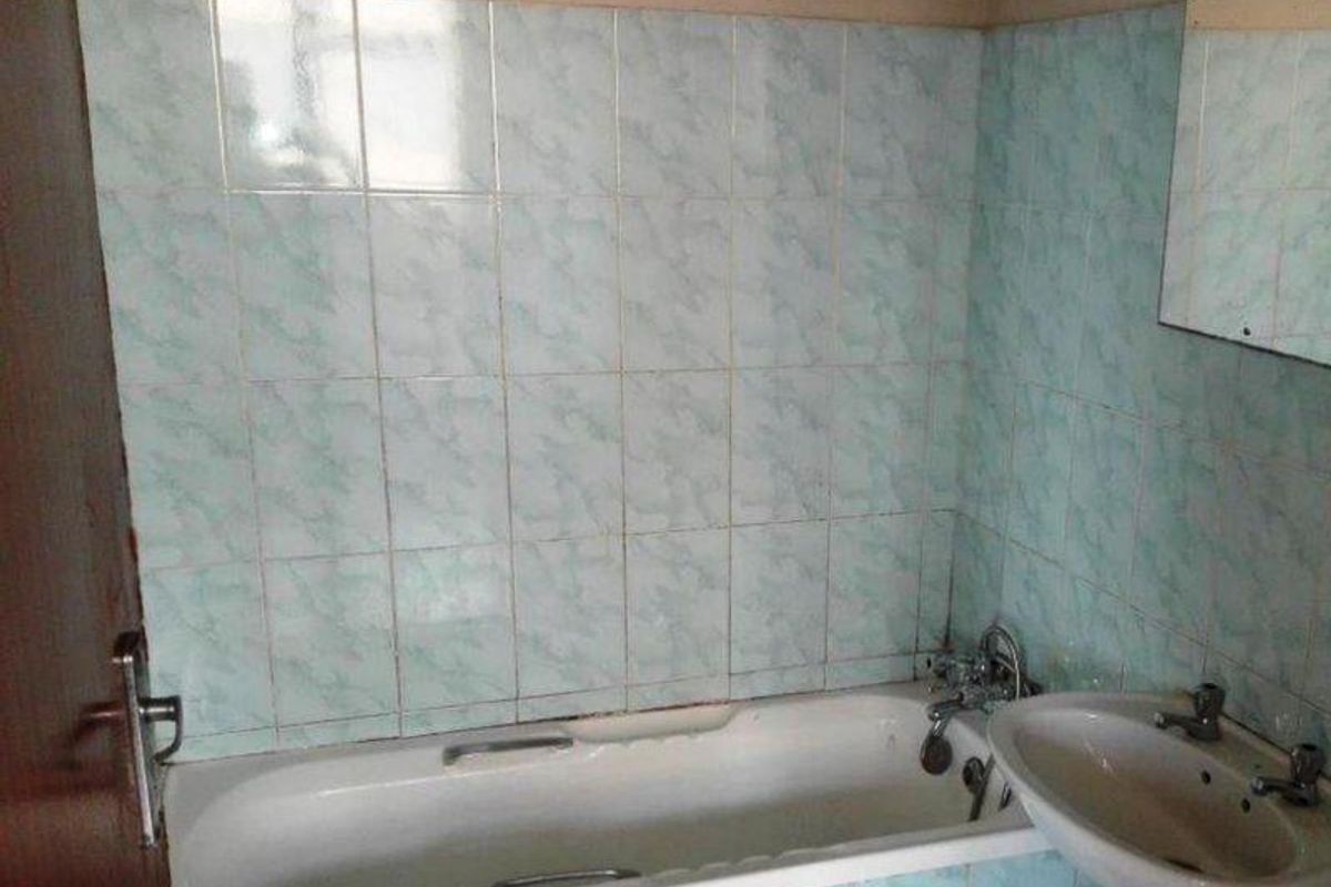 A dated bathroom featuring a standard bathtub, pedestal basin, and light blue patterned wall tiles. The space is ready for a modern renovation.
