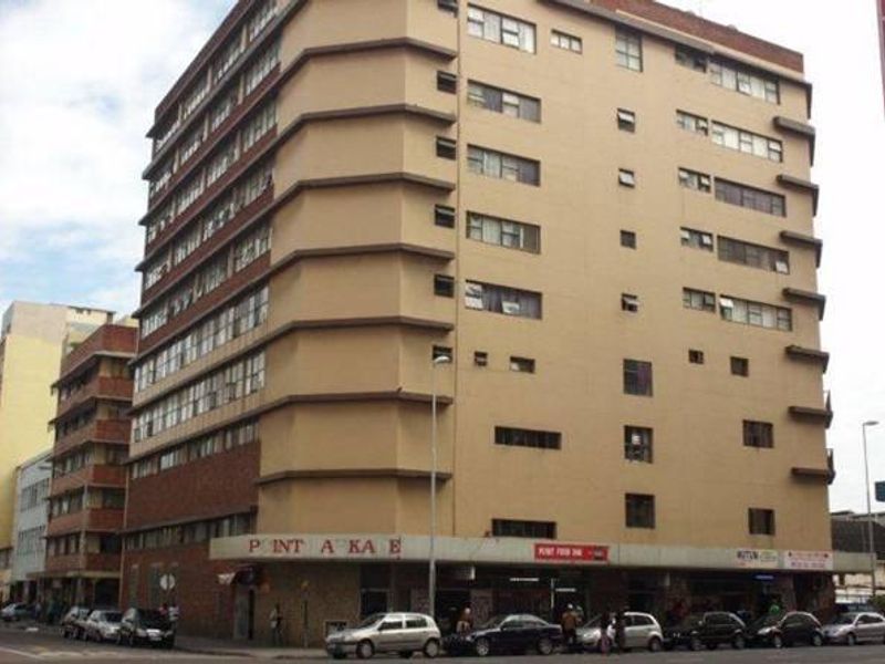 Exterior view of a multi-story apartment building featuring ground floor commercial retail spaces and a prominent street-facing facade.