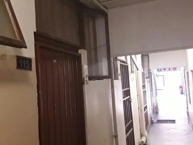 A view of an apartment building hallway featuring security gates and basic utility access points.