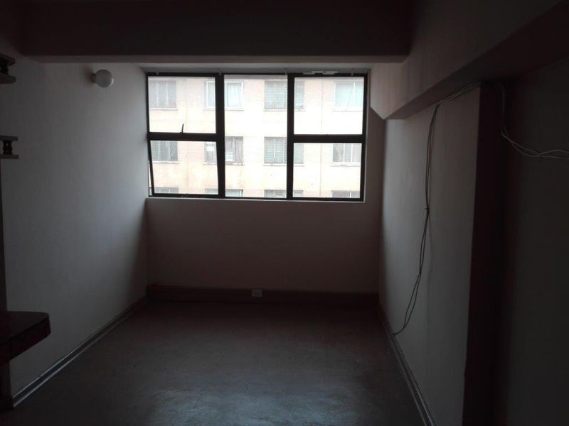 An empty bedroom featuring an aluminium-framed window and basic finishes, requiring cosmetic updates and electrical maintenance.