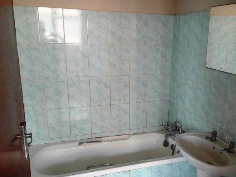 A dated bathroom featuring a standard bathtub, pedestal basin, and light blue patterned wall tiles. The space is ready for a modern renovation.