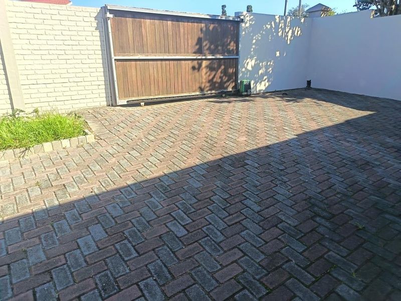 A paved front driveway area featuring a sliding gate with an integrated gate motor and perimeter walling.