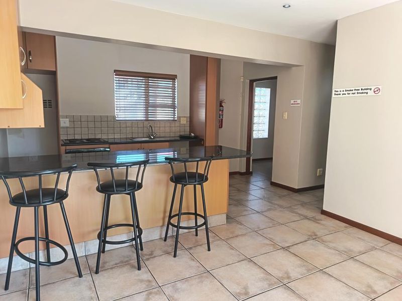 Open plan kitchen featuring granite countertops, built-in cabinetry, and a breakfast bar, flowing into a tiled living area with neutral finishes.