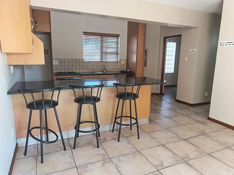 Open plan kitchen featuring a breakfast bar with granite countertops, tiled flooring, and built-in cabinetry, connecting to the living area.