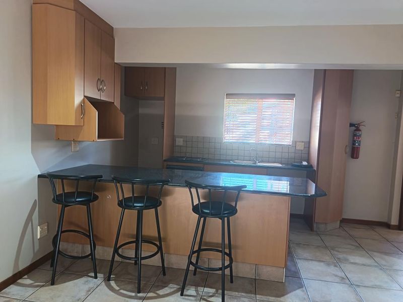 A functional kitchen featuring laminate cabinetry, granite countertops with a breakfast bar, tiled backsplash, and ceramic floor tiles.