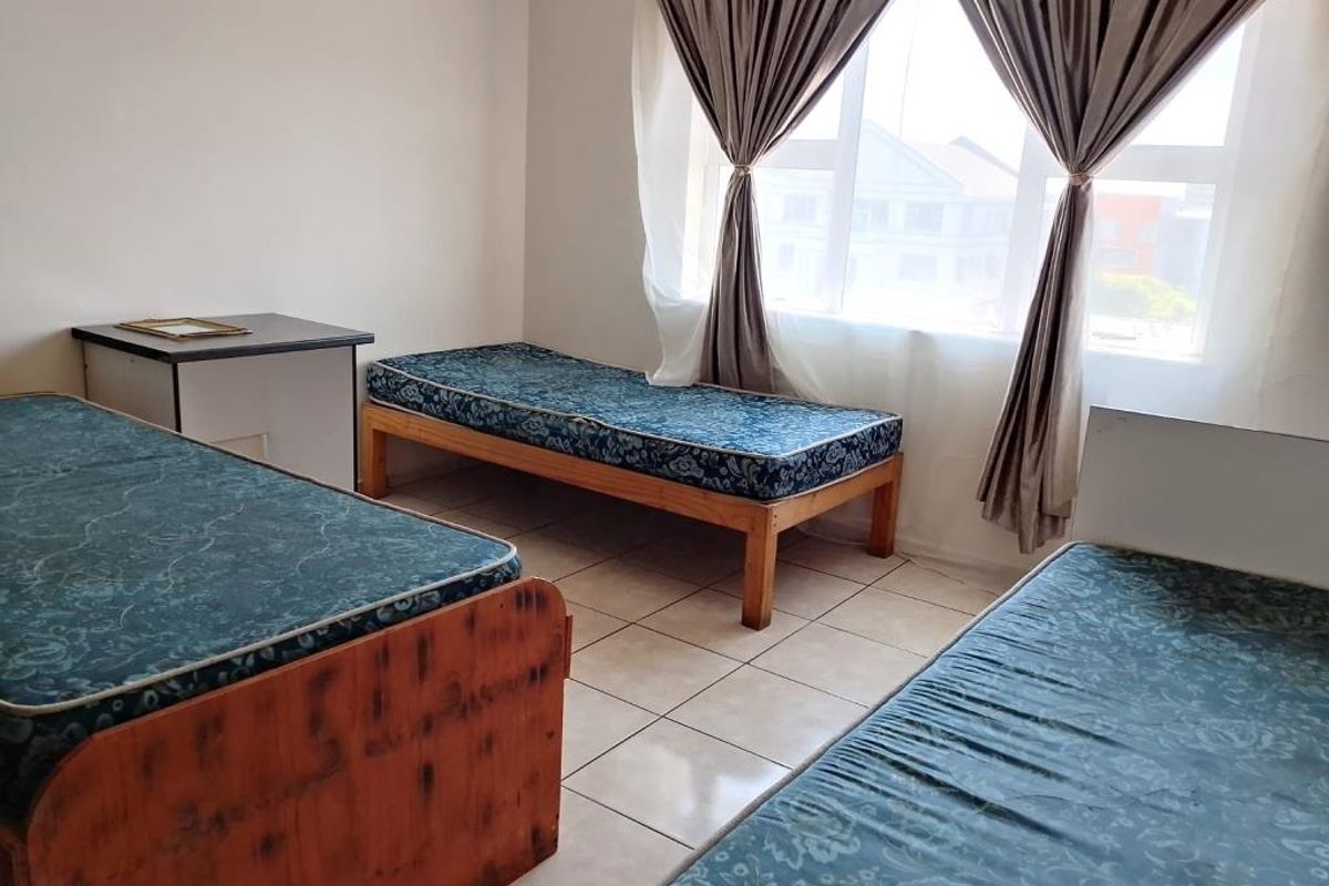 A functional bedroom featuring tiled flooring and a large window that allows for natural light.