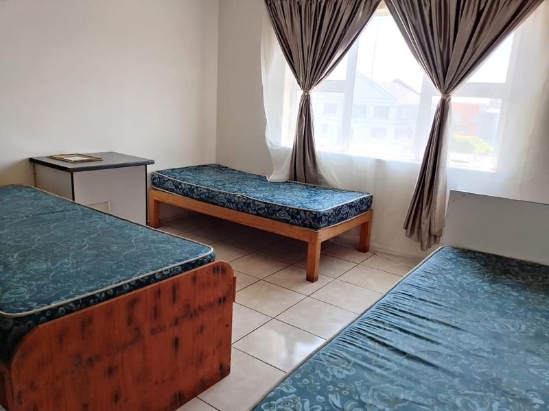 A functional bedroom featuring tiled flooring and a large window that allows for natural light.