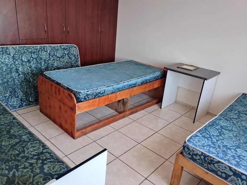 A bedroom featuring built-in wooden cupboards and tiled flooring, providing functional storage space.