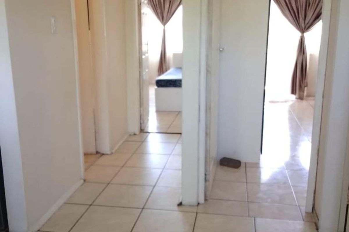 A tiled hallway providing access to multiple rooms, featuring neutral wall tones and a functional layout.