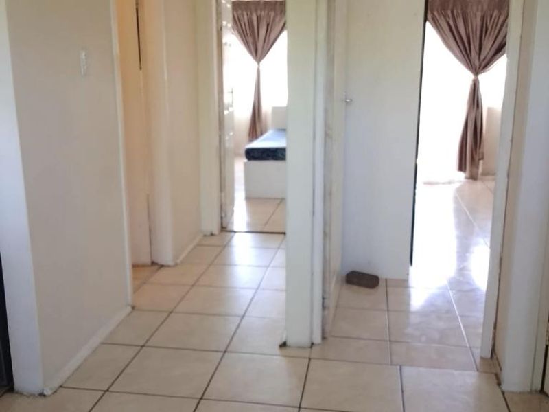 A tiled hallway providing access to multiple rooms, featuring neutral wall tones and a functional layout.