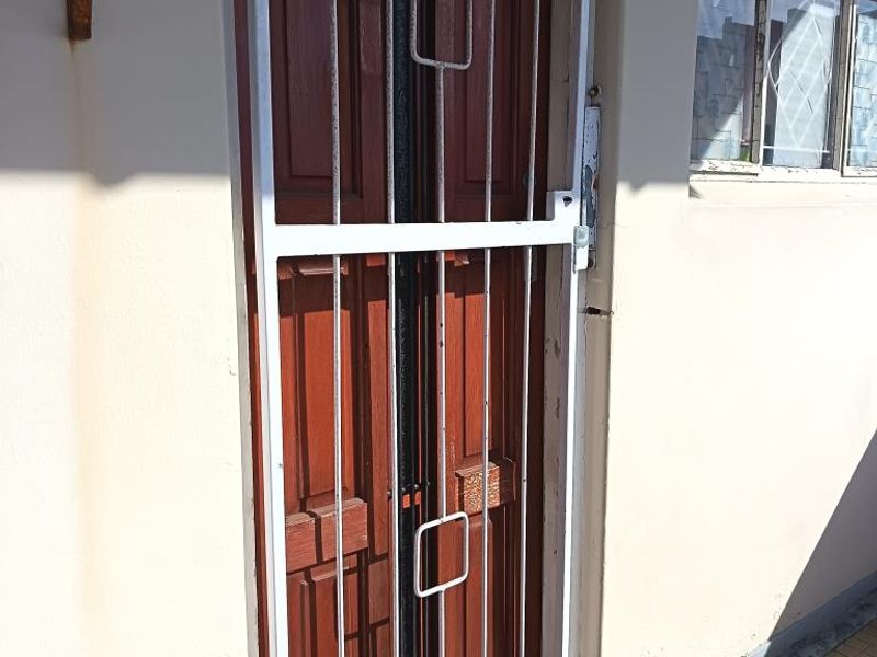An empty entrance area featuring tiled flooring and a secure metal gate leading to the street.