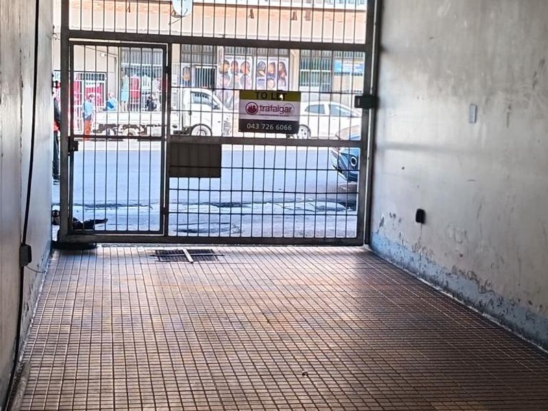 A secure gated entrance area featuring tiled flooring and signage, providing access to the apartment building premises.