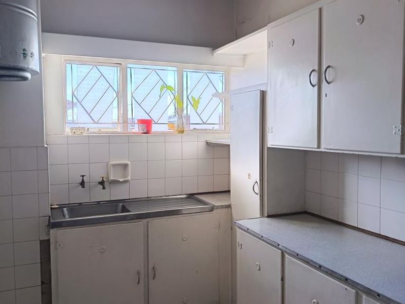 An empty bedroom featuring original parquet flooring, a security gate, and access to an outdoor area, requiring cosmetic updates to the ceiling and floor.