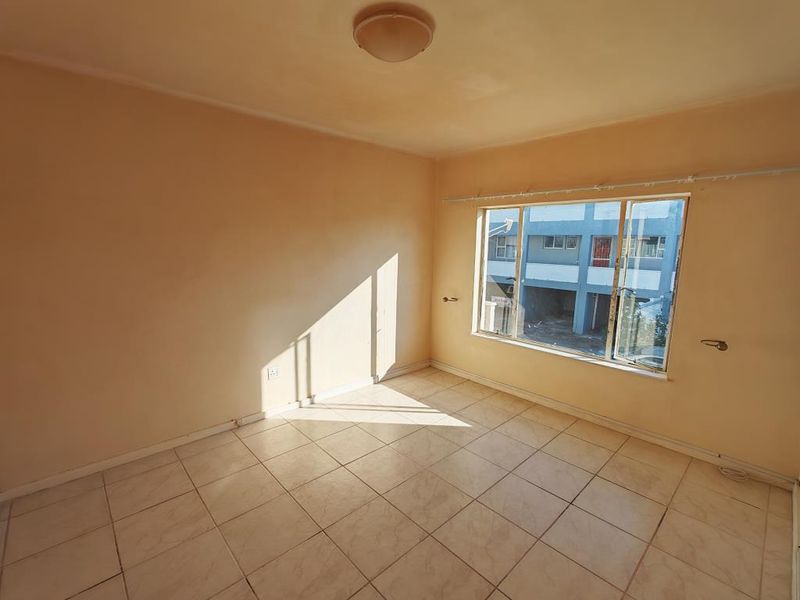 An empty bedroom featuring tiled flooring and a large sliding window, providing a blank canvas for personalization.