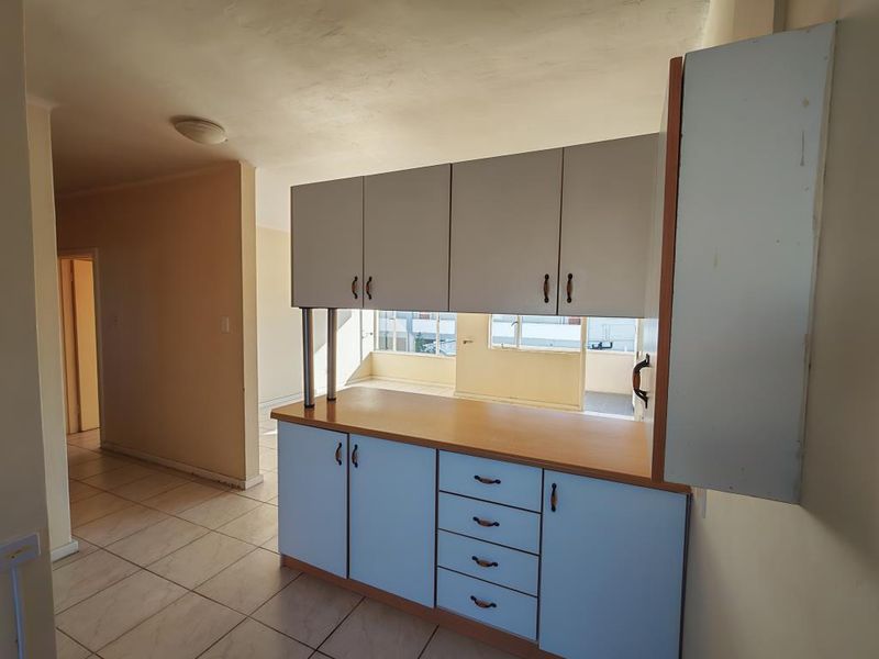 A dated kitchen area featuring built-in cabinetry with laminate countertops and tiled flooring, offering a functional layout ready for modernization.