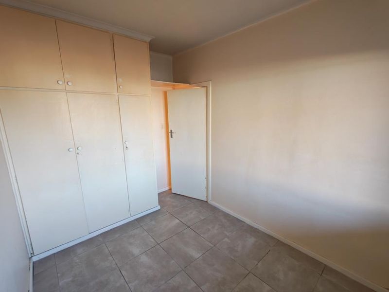 An empty bedroom featuring tiled flooring and built-in cupboards, offering a blank canvas for potential interior updates.