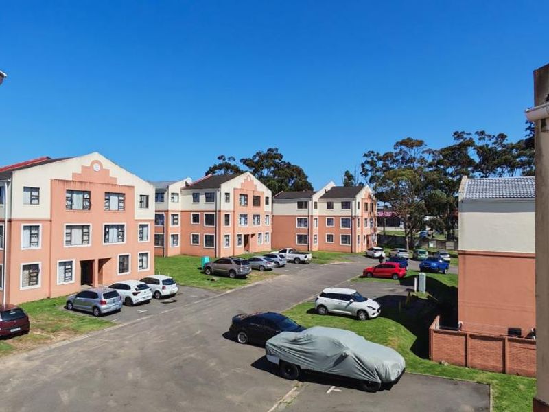 View of the apartment complex exterior, featuring multi-story residential buildings, paved parking areas, and established landscaping.