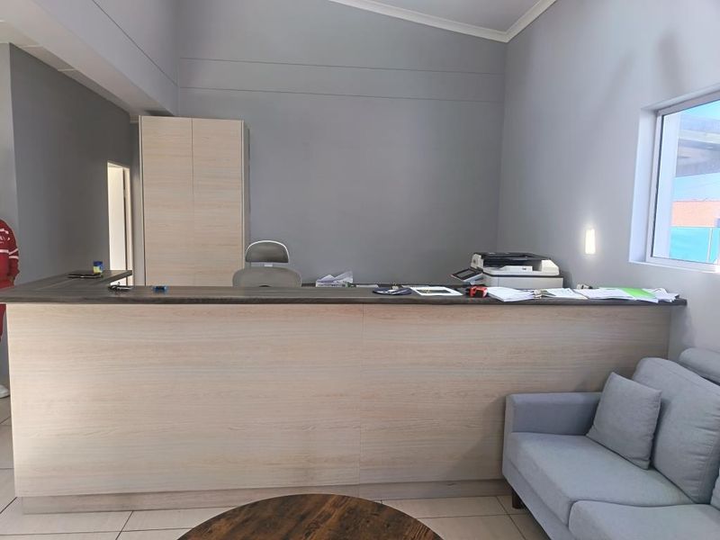 A professional office reception area featuring a custom built-in desk, integrated storage cabinetry, and neutral grey wall finishes.