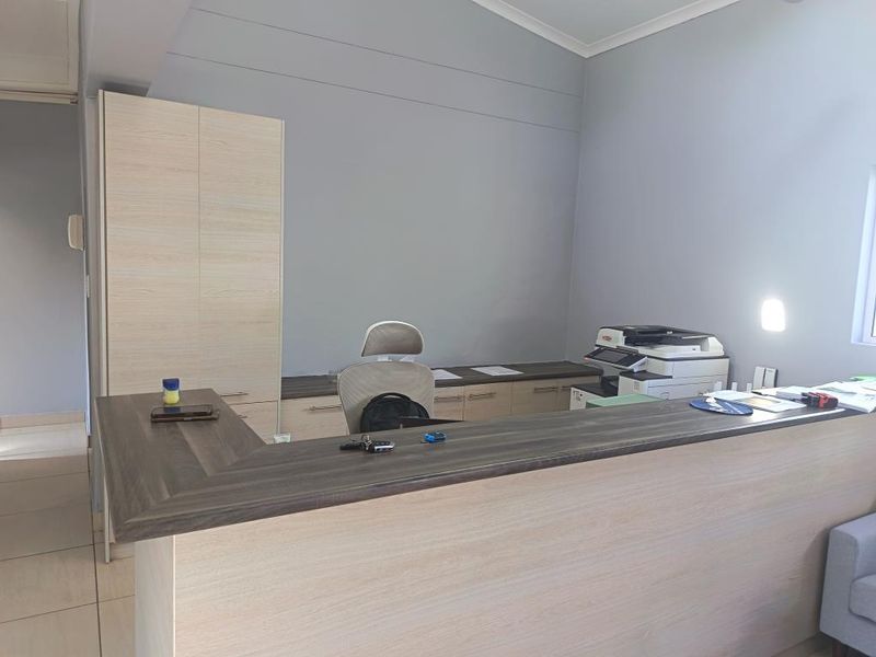 A professional office space featuring a built-in reception desk, integrated cabinetry, and neutral wall finishes, suitable for a commercial workspace.