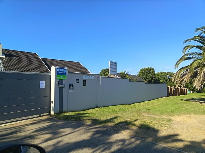Front exterior view of a commercial property featuring a perimeter wall, sliding gate, and professional signage for a dental practice.