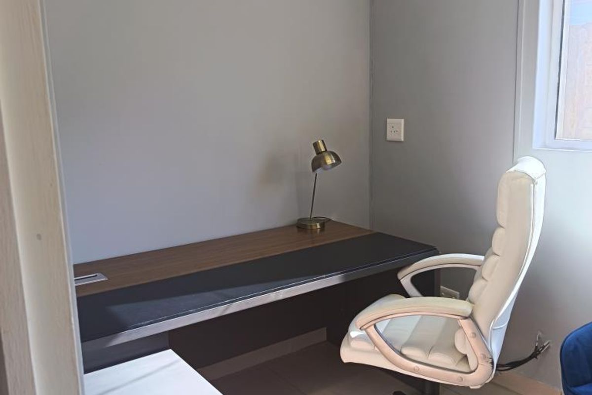 A compact, functional office space featuring tiled flooring, neutral wall finishes, and a window providing natural light.