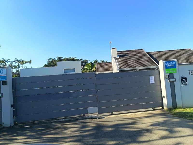 Front view of the commercial property featuring a secure sliding gate, perimeter wall, and tiled roof structure.
