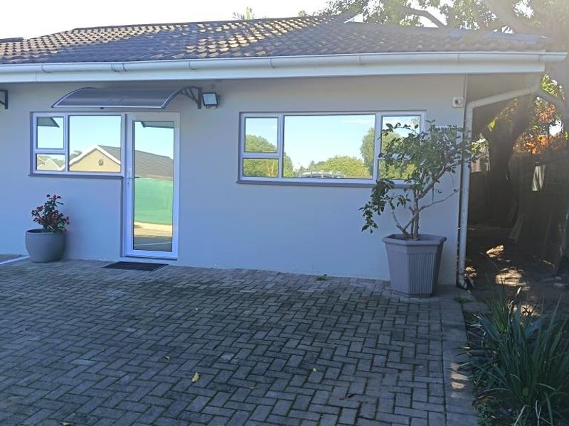 Rear exterior view of the commercial property featuring a paved courtyard, tiled roof, and modern aluminium window and door frames.