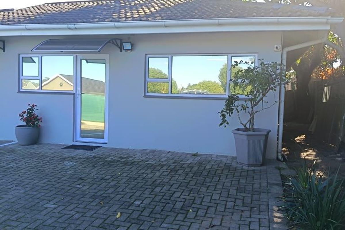 Rear exterior view of the commercial property featuring a paved courtyard, tiled roof, and modern aluminium window and door frames.