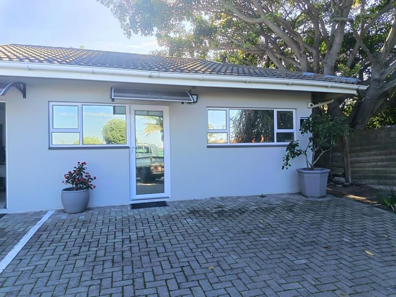 Front exterior view of a commercial building featuring a paved driveway, aluminium window frames, and a covered entrance.