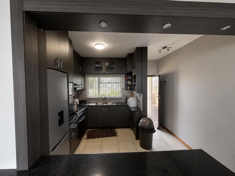 A well-maintained kitchen featuring dark wood cabinetry, granite countertops, integrated appliances, and tiled flooring, offering a functional and modern workspace.