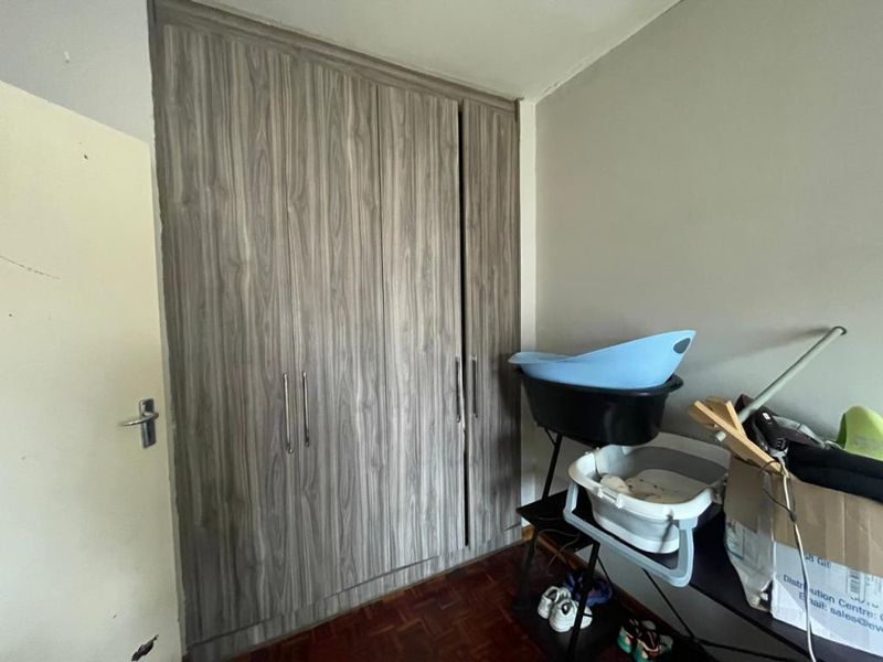 A bedroom featuring built-in wood-grain cupboards and parquet flooring, offering practical storage space.