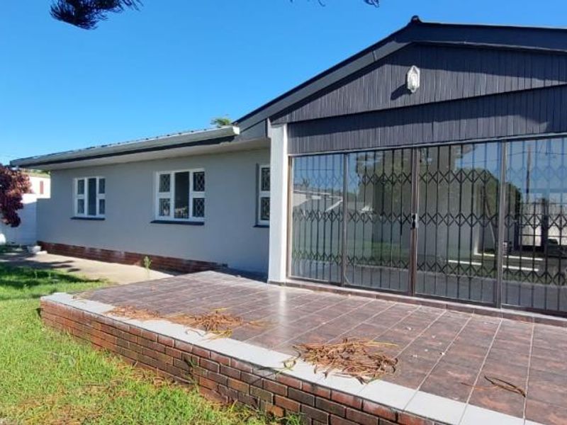 Rear view of the house featuring a tiled patio area, sliding glass doors with security gates, and a well-maintained lawn.