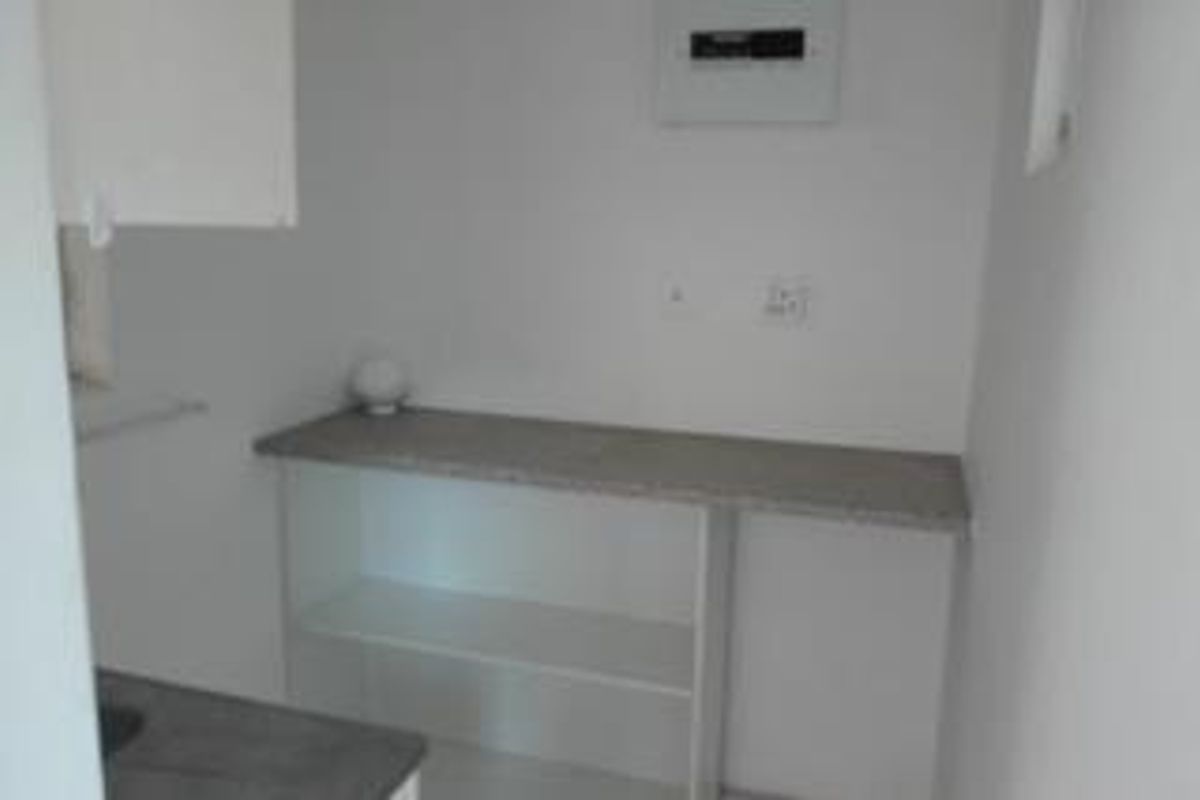 A functional utility space featuring a built-in countertop, open shelving, and an accessible electrical distribution board.