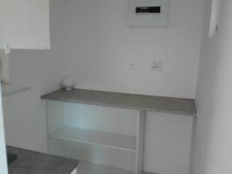A functional utility space featuring a built-in countertop, open shelving, and an accessible electrical distribution board.