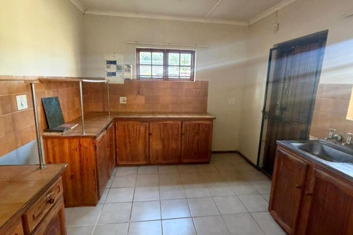 A functional kitchen featuring wooden cabinetry, tiled countertops, and tiled flooring, offering a blank canvas for potential modernization and renovation.